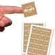 A square kraft label with white print reading White Print Kraft Labels is held on a fingertip above two full sheets of matching customised stickers. Each sheet contains multiple brown labels with subtle vertical stripes and white text, ideal for packaging or branding.