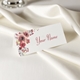 Personalised wedding place card with your name in elegant design on folded white cardstock. Set on a softly draped ivory tablecloth, creating a sophisticated and timeless look.