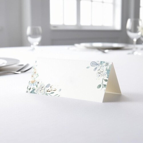 blank wedding place card with an elegant design printed on folded white cardstock, ready to write your names. Placed on a table set for a formal event, with plates, cutlery, and wine glasses in the softly blurred background.