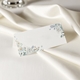 wedding place card in elegant design printed on folded white cardstock ready for you to write your names. Set on a softly draped ivory tablecloth, creating a sophisticated and timeless look.