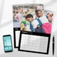 Two personalised photo wall calendars displayed on a white surface with a smartphone and pen nearby. The August 2026 calendar features two children lying on a playmat with toys, one asleep and one smiling. The July 2026 calendar behind it shows a young girl posing outdoors. Both calendars have a black border, wire binding, and a central hanging hook.