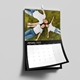 An A4 wall calendar for January 2025 with a sleek black design. The page displays a photo of a family lying on grass, with a monthly grid below. The calendar has spiral binding and a hanging hook, mounted on a grey wall.