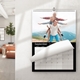 Personalised wall calendar showing the month of September 2026 with a black border and wire binding. The photo features a smiling man giving two children piggyback rides, all with arms outstretched like aeroplanes, against a scenic mountain backdrop. The calendar hangs on a white wall in a modern, sunlit room with a visible plant and sofa in the background.