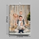 An A4 wall calendar with dimensions of 210mm width and 297mm height, featuring a family portrait of four in a cosy, festive setting. The family is seated in front of a rustic wooden backdrop with Christmas lights and decorations. The calendar has a spiral binding with a hanging hook.