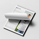 A 2026 wall planner calendar lies open on a flat surface, showing the month of April. The layout includes a vertical list of days with lined spaces for daily notes. The right side features a partial photo of a smiling young child shielding their eyes from the sun. The calendar page is being turned, and it is spiral-bound with a central hanging hook, combining function with a personal touch.