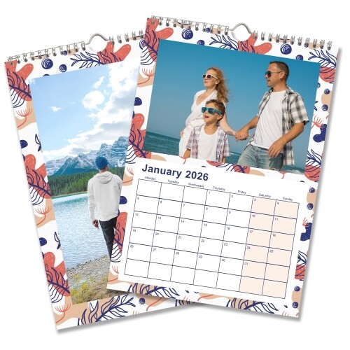 Colourful wall calendar open to January 2026, featuring a family photo at the beach with a blue and coral abstract border. The adjacent page displays a scenic mountain photo with the same decorative frame. The calendar has a clean grid layout with bold dates.