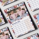 November 2026 wall calendar featuring a photo of a young girl posing confidently in a pink jacket and heart-patterned leggings. Surrounded by a colourful decorative border, the calendar is wire-bound with a hanging hook for easy display. Multiple calendar pages are laid out in the background, showcasing a cohesive and playful design.