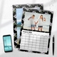 Floral wall calendar for August 2026 featuring two smiling girls by the seaside, one with prosthetic limbs and the other making a peace sign. The calendar has a black background with purple and white flowers. A smartphone and pen rest nearby on the white desk surface, giving a casual and modern feel.