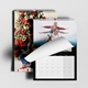 Two A3 wall calendars with a sleek black design. One displays a Christmas scene with a decorated tree, while the other shows a family outdoors with a page being turned. Both calendars feature monthly grids, spiral bindings, and hanging hooks.