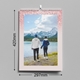 An A3 pink glitter-themed photo calendar displaying the July 2025 page. The picture shows a young child kissing a baby on a white bench. The calendar is wire-bound, measuring 420mm by 297mm, with a month grid layout.