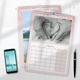 An A3 wall calendar for July 2025 with a pink glitter border. The page features a photo of a young child kissing a baby on a bench, with a monthly grid below. A second calendar with a lake and mountain scene is partially visible. A smartphone and pen are placed next to the calendars.