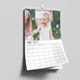 July 2026 wall calendar hanging on a wall, featuring a smiling young boy in a white vest playing with bubbles outdoors. The calendar page is slightly curled, revealing the clean and spacious layout of the monthly grid below the photo.