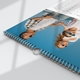 Close-up of a 2025 A4 photo calendar showing the spiral binding and hanging hook. The featured image displayed can be any photo of your choice. Part of the monthly grid is visible at the top.