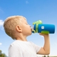 A boy drinking from a blue and green water bottle with a personalised name label attached, featuring a colourful design. The boy is outdoors against a clear blue sky, showing the use of name labels for easy identification of children's belongings