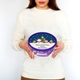 Woman holding a Cadbury Heroes tub with a personalised Christmas sticker. The sticker features Santa, a reindeer, an elf, and a decorated tree, with the message 