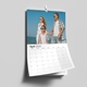 A 2025 A3 photo calendar open to April, featuring a family of three in sunglasses standing on a beach with the ocean and clear sky in the background. The calendar page is slightly curled.