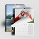 Two A3 photo calendars for 2025, one showing a blank month page being turned over. The top calendar features a family in superhero costumes, and the other shows a person in a hoodie by a mountain lake.