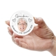 Round ceramic bauble held in a hand, featuring a photo of an elderly woman with glasses and short white hair. The word 