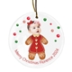 Personalised ceramic Christmas bauble featuring a baby’s face on a gingerbread girl body, decorated with icing and hearts. Surrounded by festive red and green dots, the text reads 