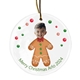 Personalised ceramic Christmas bauble featuring a child’s smiling face on a gingerbread man body decorated with icing and buttons. Surrounded by festive red and green dots, the text reads 