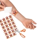 A hand applying a red star-shaped temporary tattoo reading Happy Birthday! with a man's face onto a forearm. A sheet of matching tattoos and an orange-handled pair of scissors are visible nearby, ready for use.