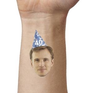 Close-up of an arm featuring a temporary tattoo with a man's face wearing a blue party hat marked 