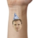 Close-up of an arm featuring a temporary tattoo with a man's face wearing a blue party hat marked 