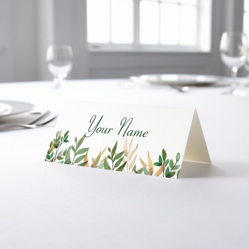 Personalised wedding place card with your name in elegant design on folded white cardstock. Placed on a table set for a formal event, with plates, cutlery, and wine glasses in the softly blurred background.