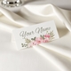 Personalised wedding place card with your name in elegant design on folded white cardstock. Set on a softly draped ivory tablecloth, creating a sophisticated and timeless look.