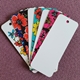 Pack of blank bookmarks fanned out on a purple surface. Some bookmarks feature vibrant floral borders in red, yellow, pink and blue, while others are fully white and ready to be personalised. Includes top hole for easy use in creative or custom craft projects.