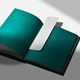 Blank white bookmark with a top hole placed on the open pages of a dark green book. The bookmark has a smooth finish and rounded corners, ideal for personalised printing, custom messages or creative craft use. Set against a clean, shadowed background.