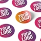 Personalised 37mm round labels with a custom logo design. The stickers are printed on a sheet and come in various shades of pink, purple, and orange. One label is partially peeled to show the adhesive backing. Ideal for branding, packaging, or crafts.