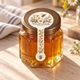 Wildflower honey jar with a flower and bee lollipop seal sticker running from the gold lid down the front.
