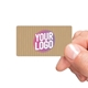 Hand holding a rectangular kraft label with a ribbed texture, featuring a personalised design with the text Your Logo in bold pink and white. Ideal for customised branding on various products.