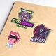 A set of colourful vinyl die-cut stickers on a beige surface. Designs include a Rebel Monkey Gaming sticker with a fierce monkey face, an Ultimate Airsoft soldier in a gas mask, a dripping tongue and lips, and a Vinyl Stickers label in blue text.