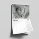 A 2025 A4 photo calendar opened to February, featuring a black-and-white image of baby feet cradled in adult hands. The calendar is spiral-bound with a white hanging hook, showcasing a clean grid layout for daily notes and reminders.