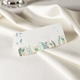 wedding place card in elegant design printed on folded white cardstock ready for you to write your names. Set on a softly draped ivory tablecloth, creating a sophisticated and timeless look.