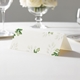 wedding place card with an elegant design on folded white cardstock ready to write your name on. Displayed on a white tablecloth with wine glasses, plates, and a floral centrepiece in the softly blurred background.