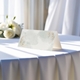 blank wedding place card printed with an elegant design on folded white cardstock ready to write your names on. Displayed on a table with a flowing white tablecloth, with soft natural light and white roses in the background.