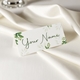 Personalised wedding place card with your name in elegant design on folded white cardstock. Set on a softly draped ivory tablecloth, creating a sophisticated and timeless look.