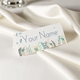 Personalised wedding place card with your name in elegant design on folded white cardstock. Set on a softly draped ivory tablecloth, creating a sophisticated and timeless look.