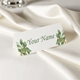 Personalised wedding place card with your name in elegant design on folded white cardstock. Set on a softly draped ivory tablecloth, creating a sophisticated and timeless look.