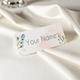 Personalised wedding place card with your name in elegant design on folded white cardstock. Set on a softly draped ivory tablecloth, creating a sophisticated and timeless look.