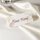 Personalised wedding place card with your name in elegant design on folded white cardstock. Set on a softly draped ivory tablecloth, creating a sophisticated and timeless look.