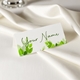 Personalised wedding place card with your name in elegant design on folded white cardstock. Set on a softly draped ivory tablecloth, creating a sophisticated and timeless look.